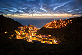 Die Lichter des Fischerdorfs Vernazza mit der typischen Krippe auf dem Hügel, Nationalpark Cinque Terre, Provinz La Spezia, Ligurien, Italien.