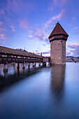 View of the Kapellbrücke bridge and the Wasserturm at sunset reflected on the Reuss river. Lucerne, canton of Lucerne, Switzerland.