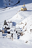 Blick auf die Kirche und das Dorf Riale im Winter von der Straße zur Maria-Luisa-Hütte und dem Hochtal von Formazza. Riale, Formazza, Valle Formazza, Verbano Cusio Ossola, Piemont, Italien.