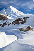 View of a hut near the Maria Luisa refuge and Kastelhorn in the high Formazza Valley in winter. Riale, Formazza, Valle Formazza, Verbano Cusio Ossola, Piedmont, Italy.