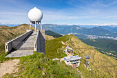 Blick vom Gipfel des Monte Lema (Schweiz) auf den Lago Maggiore (Italien) mit seiner Seilbahn, Schutzhütte, Meteostation und Observatorium. Luganer Voralpen, Kanton Tessin, Schweiz.