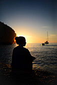 Silhouette einer jungen Frau, die einen Sonnenuntergang an einem schönen Strand genießt