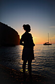 Silhouette einer jungen Frau, die einen Sonnenuntergang an einem schönen Strand genießt