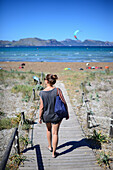 Junge Frau am Strand von Port de Pollenca, dem idealen Ort zum Kitesurfen auf Mallorca, Spanien