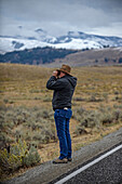 Mann beobachtet mit einem Fernglas die Tierwelt im Yellowstone-Nationalpark, USA