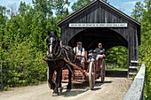 Historischer Karren für den Transport von Touristen durch das überdachte Holzhaus aus dem Jahr 1900, historisches akadisches Dorf, Bertrand, New Brunswick, Kanada, Nordamerika