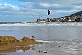 Kitesurfing on the sea in front of the village of houlgate seen from the town of dives-sur-mer, calvados, normandy, france