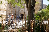 Paar auf Fahrrädern vor dem Eingang der Kathedrale von Maguelone, restaurierte Inselkirche, villeneuve-les maguelone, herault, occitanie, frankreich