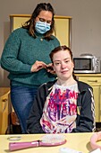 Monitor with a resident for a beauty session (hairdressing and manicure), care home for adults with moderate mental disabilities, residence du moulin de la risle, le moulin rouge, rugles, eure, normandy, france