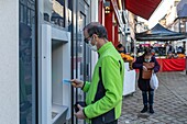 Autonomous resident at an atm with his debit card, care home for adults with mental disabilities, residence la charentonne, adapei27, association departementale d'amis et de parents, bernay, eure, normandy, france