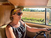 Woman at the steering wheel for a drive in the countryside in a volkswagen combi, manche, normandy, france