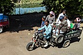 Gruppe von Arbeitern auf einem LKW-Motorrad, die an einem Bewässerungskanal entlangfahren, Luxor, Ägypten, Afrika