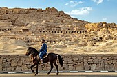 Man on horseback in front of the valley of the nobles where the tombs of many nobles from the new empire can be found, luxor, egypt, africa