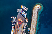 Aerial view of colourful boats and fishing vessels moored in the turquoise waters of the harbour of Ponza with the lighthouse and rocks at sunset, Ponza island, Archipelago Pontino, Latina province, Latium, Italy