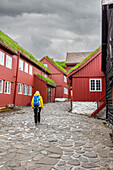 Tourist geht durch die engen Gassen des hystorischen Stadtzentrums von Tinganes, Torshavn, Streymoy Insel, Färöer Inseln, Dänemark, Europa