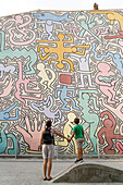 Mother and little boy child admiring the Keith Haring artistic mural named Tuttomondo, Pisa, Tuscany, Italy