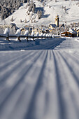 Leere, schneebedeckte Straße zum Alpendorf Celerina, Kanton Graubünden, Engadin, Schweiz