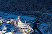 Schneebedeckte Kirche San Geer und zugefrorener Inn, Scuol, Kanton Graubünden, Engadin, Schweiz