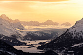 Verschneite Engadiner Alpenseen und das Dorf Maloja bei Sonnenuntergang, Kanton Graubünden, Schweiz