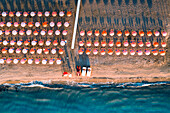 Aerial view of beach umbrellas in a row on sand beach washed by waves, Vieste, Foggia province, Gargano, Apulia, Italy