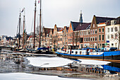 Traditionelle Häuser und Boote entlang des Spaarne-Kanals in der Haarlemer Altstadt, Amsterdam, Nordholland, Niederlande