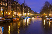 Lichter traditioneller Häuser, die sich in der Abenddämmerung in der Gracht spiegeln, Amsterdam, Nordholland, Niederlande