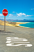 Rotes Stoppschild auf leerer Straße in der Nähe des Strandes Sotavento, Naturpark Jandia, Costa Calma, Fuerteventura, Kanarische Inseln, Spanien