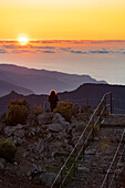 Wanderer genießt den Sonnenuntergang auf dem Gipfel des Pico Ruivo, Madeira, Portugal