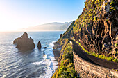 Old coastal road with Ilheus da Rib and Ribeira da Janela sea stack rocks on background, Porto Moniz, Madeira, Portugal