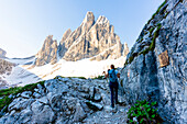 Hiker woman on mountain path from Rifugio Zsigmondy Comici to Pian di Cengia hut, Sesto Dolomites, South Tyrol, Italy