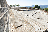 Tourists admiring the old theatre area and staircase of the Phaistos Palace, Bronze Age archeological site, Crete, Greece