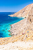 Wanderer beim Abstieg auf den Felsen zum idyllischen Strand Glyka Nera im Sommer, Hora Sfakion, Insel Kreta, Griechenland
