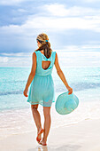 Beautiful woman in turquoise dress walking to the sea on idyllic beach, Barbuda, Antigua & Barbuda, Caribbean, West Indies