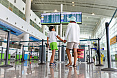 Glücklicher kleiner Junge mit Mutter beim Warten auf einen Flug im Abflugbereich des Flughafens in den Sommerferien
