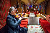 Das Innere des Transcantabrico Gran Lujo Luxuszuges auf einer Reise durch Nordspanien, Europa. Innenraum des Speisewagens. Geige Live-Musik.