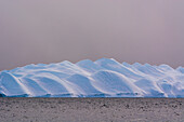 An iceberg in Ilulissat Icefjord, an UNESCO World Heritage Site, on a cloudy day. Ilulissat Icefjord, Ilulissat, Greenland.