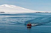 Ecotourists travel across Bockfjorden in an inflatable raft. Bockfjorden, Spitsbergen Island, Svalbard, Norway.