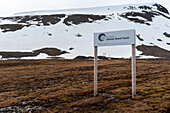 A sign for the Svalbard Global Seed Vault posted near a snow streaked mountain. Longyearbyen, Spitsbergen Island, Svalbard, Norway.