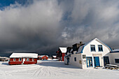 Schneebedeckte Häuser und Straßen unter einem bewölkten Himmel. Andenes, Vesteralen-Inseln, Nordland, Norwegen.