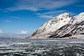 Schneebedeckte Berge und Packeis in der Bucht von Knutstad. Knutstad, Lofoten-Inseln, Nordland, Norwegen.