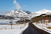 Die Nationale Touristenstraße Lofoten entlang des zugefrorenen Ostadvatnet-Sees. Ostadvatnet-See, Lofoten-Inseln, Nordland, Norwegen.