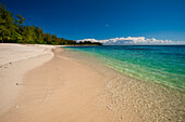 Ein tropischer Sandstrand und das klare blaue Wasser des Indischen Ozeans. Die Insel Denis, Republik Seychellen.
