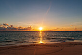 Sonnenuntergang an einem breiten tropischen Sandstrand im Indischen Ozean. Denis Insel, Die Republik der Seychellen.
