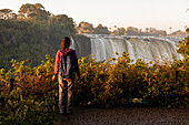 Ein Tourist genießt die majestätische Schönheit der Victoriafälle. Victoria Falls-Nationalpark, Simbabwe.