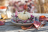 Autumn decoration, flower wreath of common heather (Calluna Vulgaris), ornamental pumpkin and autumn leaves on terrace