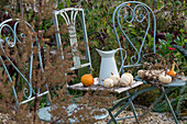 Herbststillleben, Zierkürbisse auf Gartenstühlen und Wasserkrug