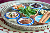Verschiedene Kräuter und Gewürze für orientalische Gerichte in kleinen Schalen, im Fokus Pfeffrminze
