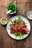 Sliced steak with green asparagus and cherry tomatoes