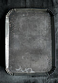 Empty metal baking tray with crumbs and stains
