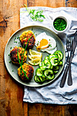 Salmon trout patties with poached egg and cucumber salad
